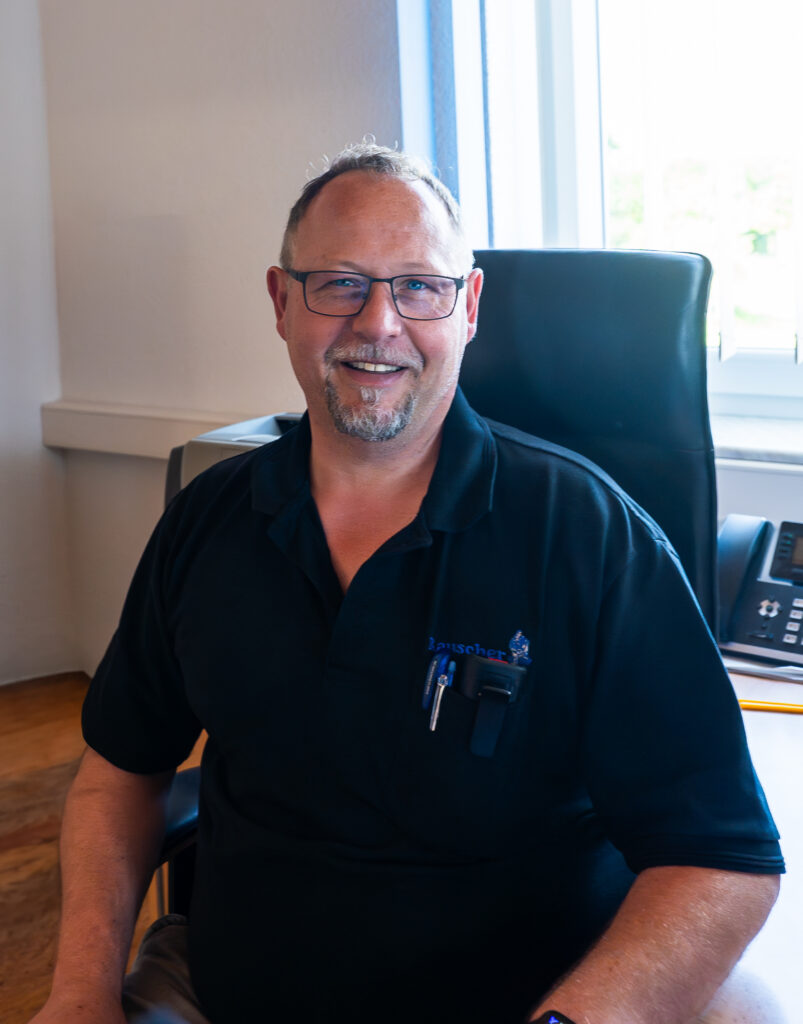 Portrait von Markus Rauscher, Geschäftsführer von Rauscher Berufsbekleidung, am Schreibtisch.